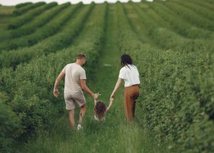 Happy family walking together through a lush green field enjoying nature and togetherness.